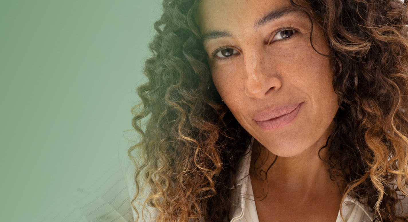 Woman with curly hair smiling against a light green background